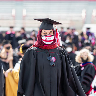 A student smiles as she walks up to cross the stage at the 2021 graduate and professional student commencement ceremony.