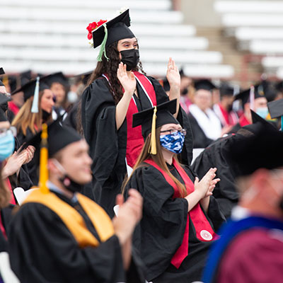 A student stands up among her fellow graduates at the 2021 IUPUI undergraduate commencement ceremony.