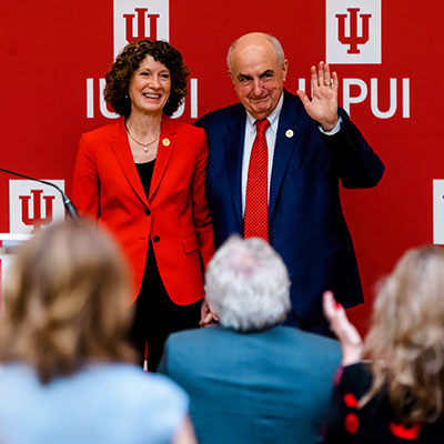 IU First Lady Laurie Burns McRobbie and President Michael A. McRobbie smile and wave from the stage