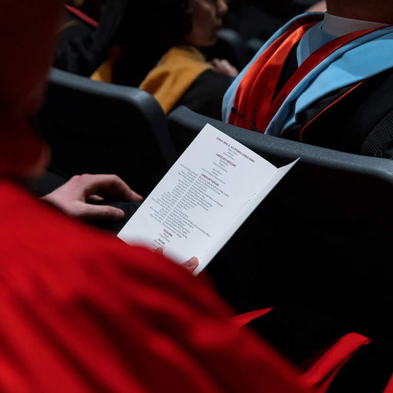 person looks at a program for honors convocation 2022