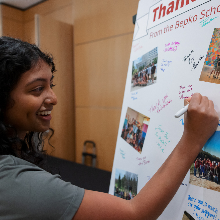 Student making a note on a Thanks board for Bepko ceremony