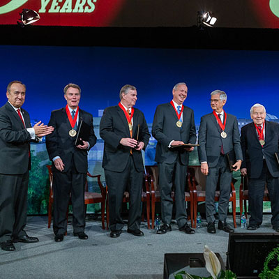 Chancellor Paydar leads applause after giving Chancellor's Medallions to 5 mayors of Indianapolis who appear to the right of him:  Mayor Joe Hogsett and former mayors Greg Ballard, Bart Peterson, Stephen Goldsmith, and Senator Richard Lugar.  All stand on a stage with a backdrop behind them.  
