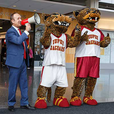 Chancellor Paydar holds a megaphone in the Campus Center with IUPUI mascots. 
