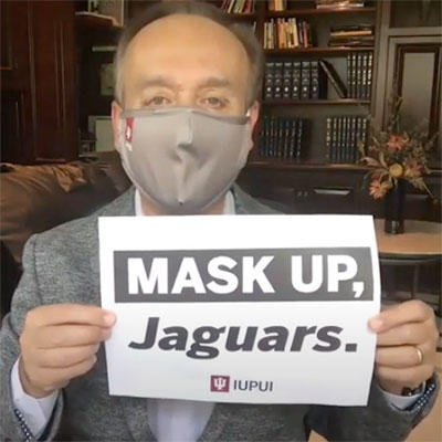 Paydar is wearing a mask and holding a sign that says mask up Jaguars