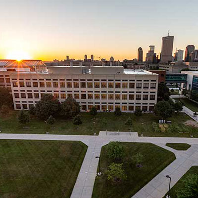 IUPUI campus buildings with Indianapolis skyline in the background.  Early morning photo with sun on horizon.