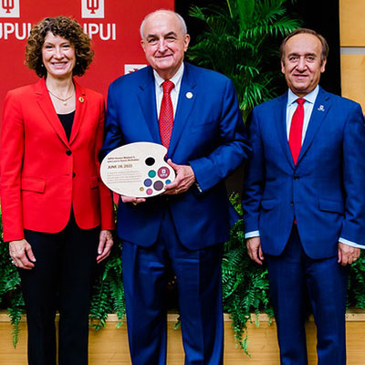 Chancellor Paydar stands with Indiana University President Michael McRobbie and Laurie Burns McRobbie.  The president is holding a painter's pallet, which is a memento created for him and Mrs. McRobbie by a graduate of Herron to mark the occasion of the ceremony.  