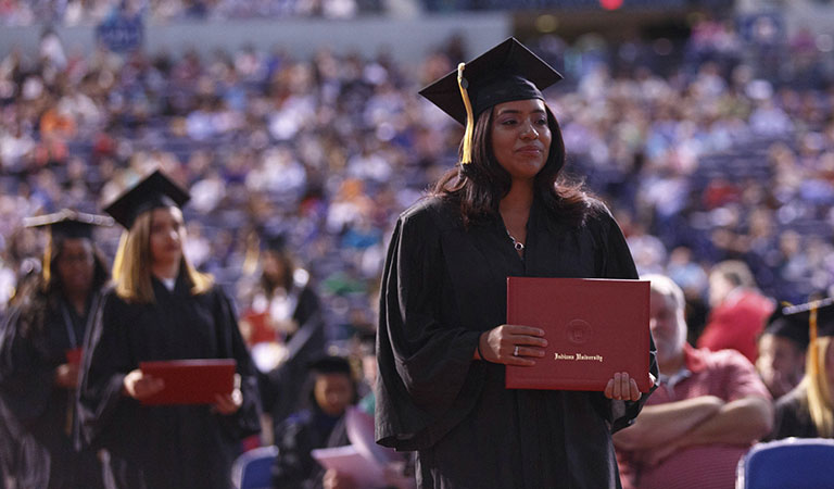 students holding diplomas after walking at commencement